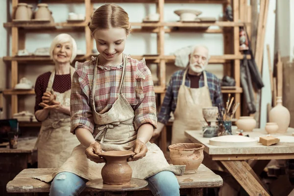 Abuela y abuelo con nieta haciendo cerámica en el taller - foto de stock