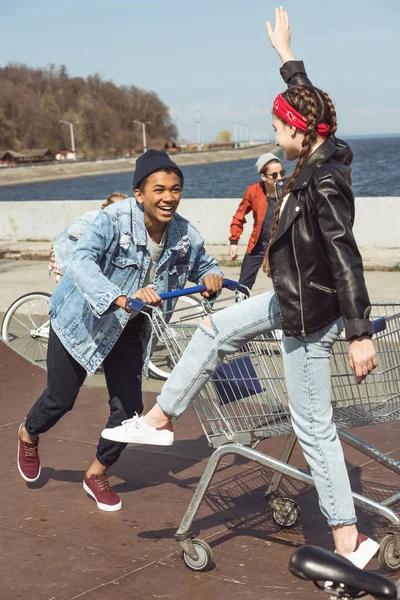 Adolescentes con carrito de compras y bicicleta - foto de stock