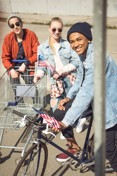 Adolescentes con carrito de compras y bicicleta - foto de stock