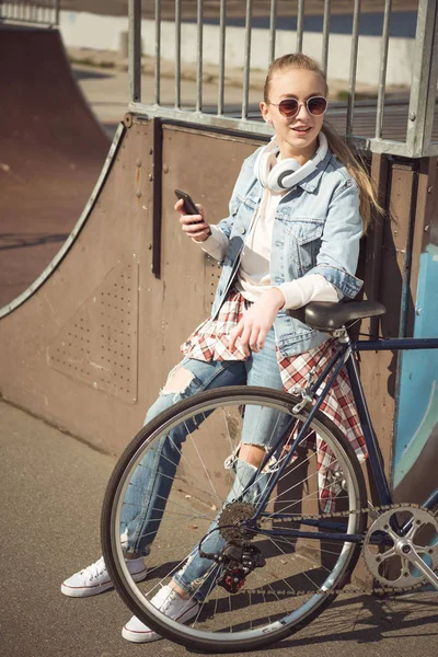 Girl with bike using smartphone — Stock Photo