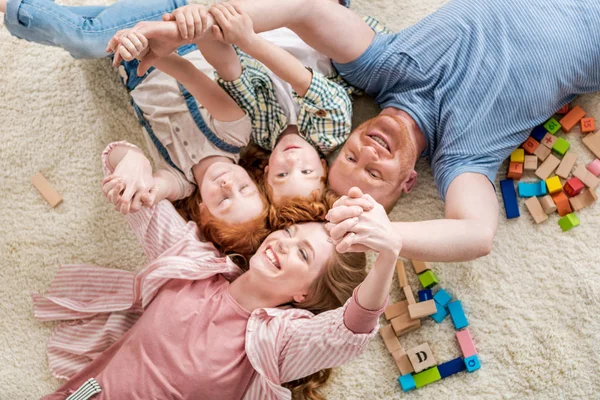 Família feliz deitada no chão — Fotografia de Stock