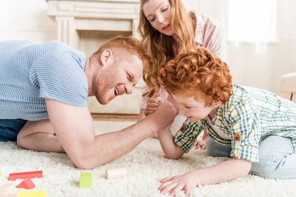Padre e hijo jugando lucha libre de brazos - foto de stock