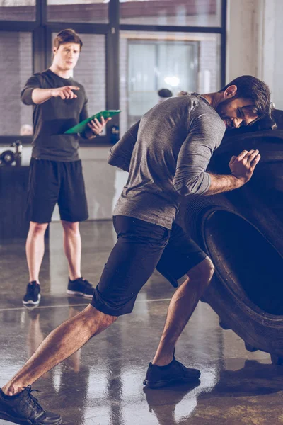 Homme tirant pneu dans la salle de gym — Photo de stock