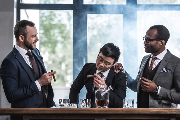 Equipo de negocios multicultural pasar tiempo, fumar cigarros y beber whisky - foto de stock