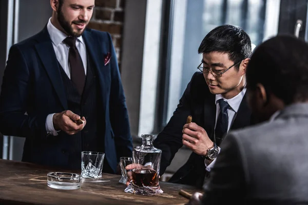 Equipo de negocios multicultural pasar tiempo, fumar cigarros y beber whisky - foto de stock