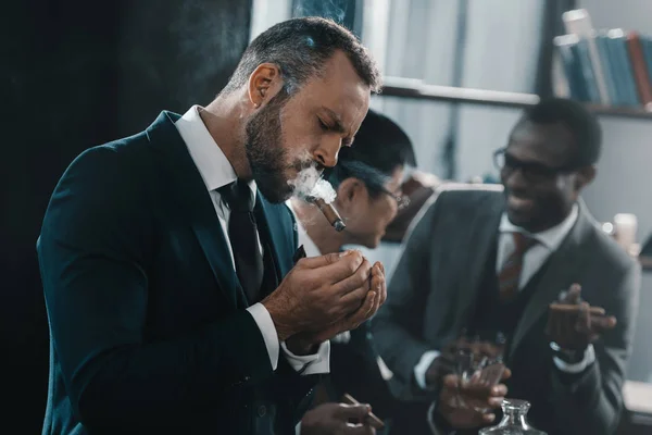 Businessman smoking cigar with multicultural business team spending time behind — Stock Photo