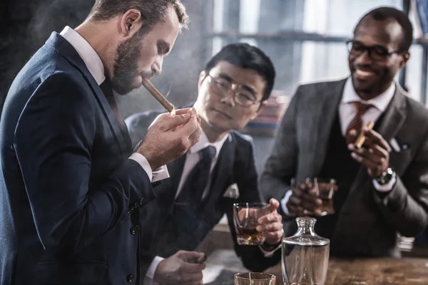 Equipo de negocios multicultural pasar tiempo, fumar cigarros y beber whisky - foto de stock