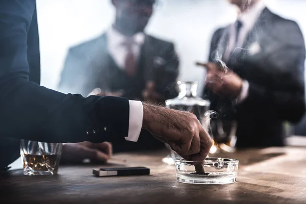 Cropped view of businessman extinguishing cigar in glass ashtray — Stock Photo