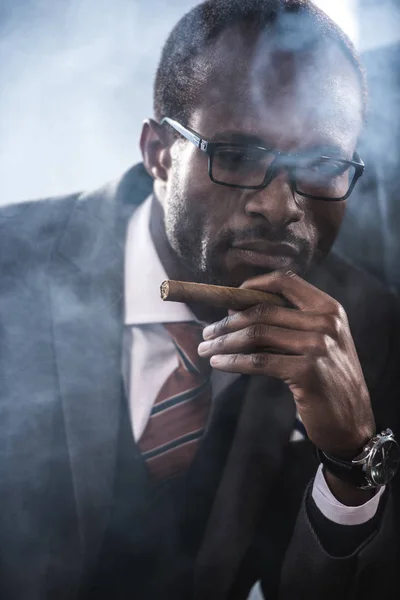 Portrait d'un homme d'affaires afro-américain confiant fumant un cigare — Photo de stock