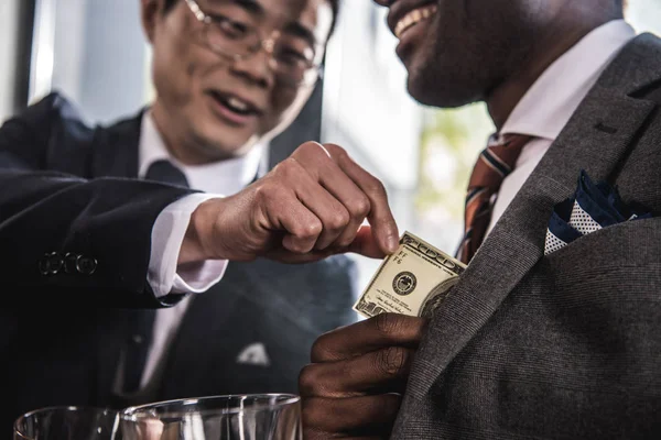 Cropped shot of two smiling businessmen talking and holding dollar banknote — Stock Photo