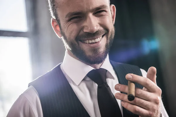 Close-up retrato de bonito sorrindo homem confiante fumar charuto dentro de casa — Fotografia de Stock