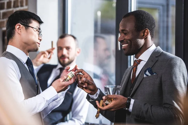 Visão lateral do empresário dando dinheiro ao colega sorridente — Fotografia de Stock