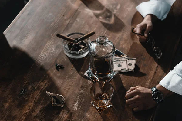 Billetes de dólar, whisky y puros en cenicero sobre mesa de madera - foto de stock