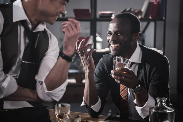 Compañeros alegres que beben alcohol mientras pasan tiempo juntos después del trabajo - foto de stock