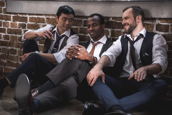 Grupo de elegantes hombres de negocios sonrientes descansando juntos después del trabajo - foto de stock