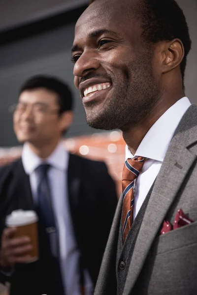Giovani uomini d'affari multietnici sorridenti che si incontrano durante una pausa caffè all'aperto, riunione del team di lavoro — Foto stock
