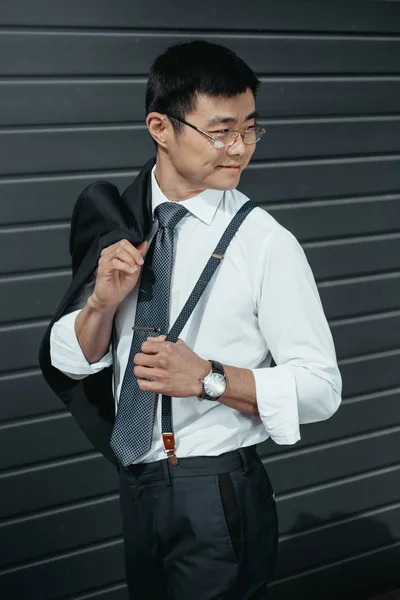 Confident stylish asian businessman posing outdoors at wall — Stock Photo