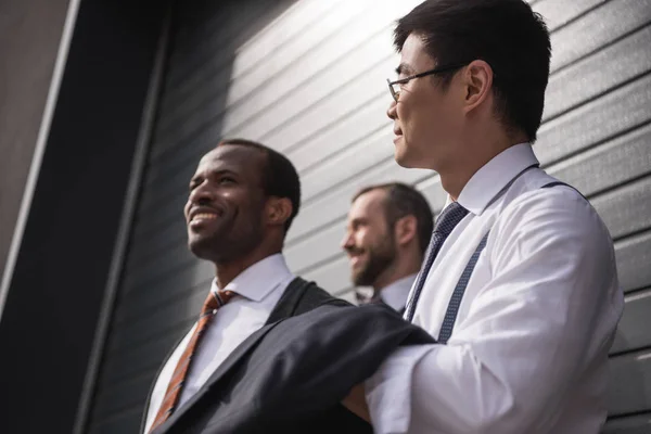 Jeunes hommes d'affaires multiethniques élégants en tenue de cérémonie debout à l'extérieur, réunion de l'équipe d'affaires — Photo de stock