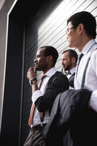 Jeunes hommes d'affaires multiethniques élégants en tenue de cérémonie debout à l'extérieur, réunion de l'équipe d'affaires — Photo de stock