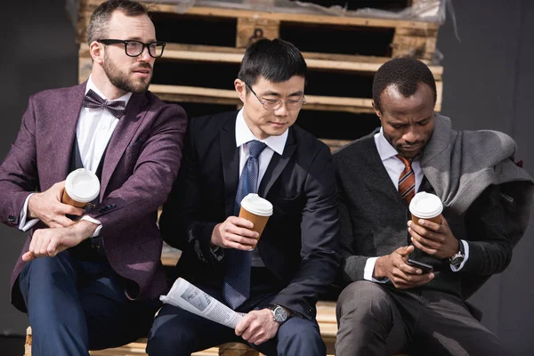 Junge multiethnische Geschäftsleute in Formalbekleidung sitzen in der Kaffeepause im Freien, Besprechung des Geschäftsteams — Stockfoto