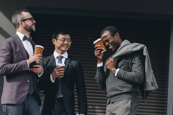 Multicultural businessmen holding paper coffee cups and standing outdoors, business people team concept — Stock Photo