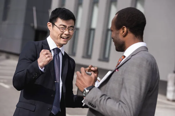 Jeunes hommes d'affaires multiethniques souriants en tenue de cérémonie célébrant le succès, réunion de l'équipe d'affaires — Photo de stock