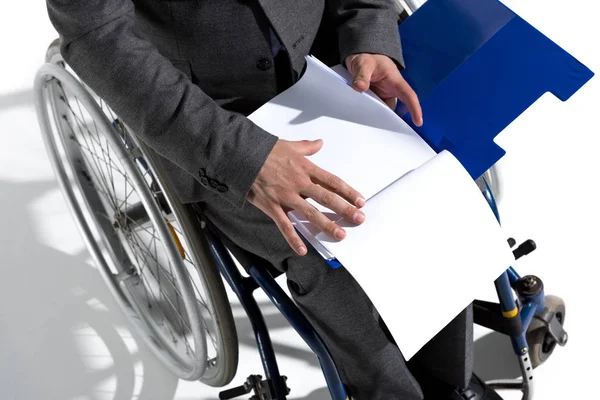 Homem de negócios em cadeira de rodas com folhas de papel em branco — Stock Photo