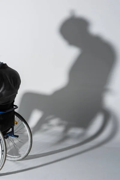 Hombre con discapacidad física en silla de ruedas con sombra - foto de stock