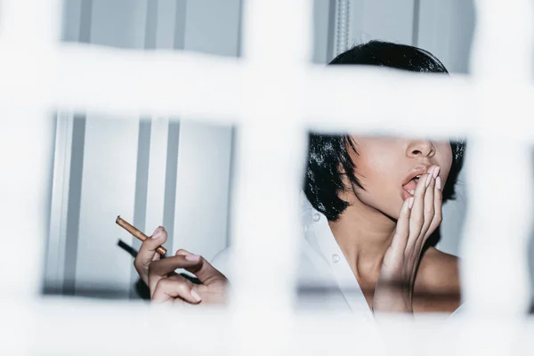 Mujer en camisa detrás de la rejilla - foto de stock