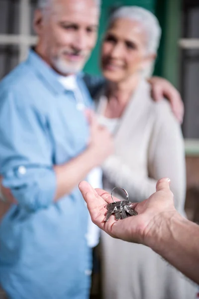 Vendeur donnant des clés aux nouveaux propriétaires — Photo de stock