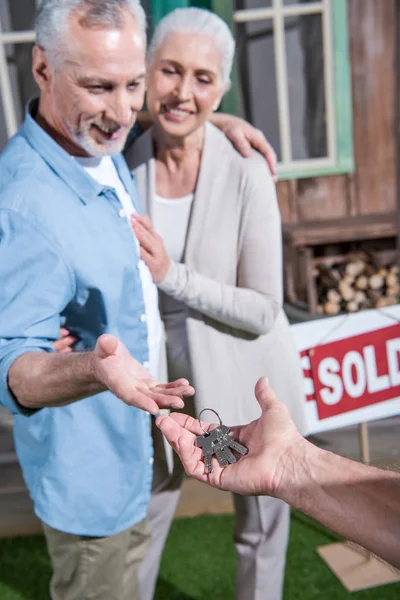 Vendeur donnant des clés aux nouveaux propriétaires — Photo de stock