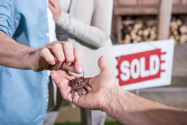 Vendedor dando llaves a los nuevos propietarios - foto de stock