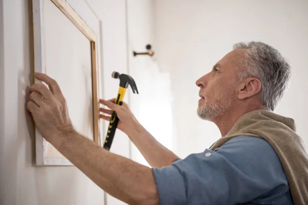 Man hanging picture on wall — Stock Photo