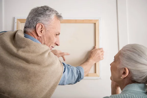 Senior couple hanging picture on wall — Stock Photo