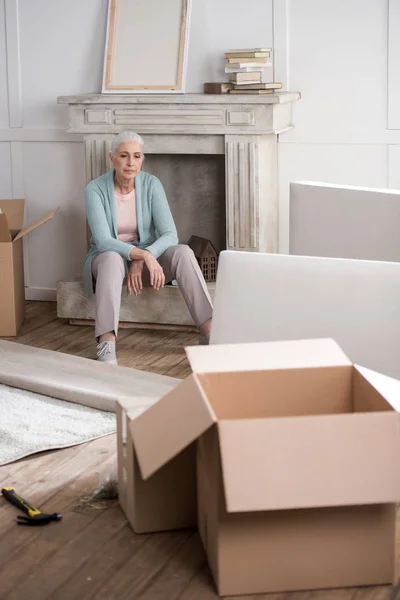 Tired woman sitting on fireplace — Stock Photo