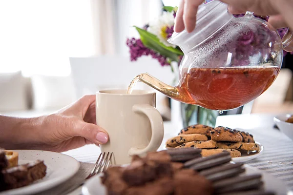 Mann gießt beim Frühstück Tee in Tasse — Stockfoto