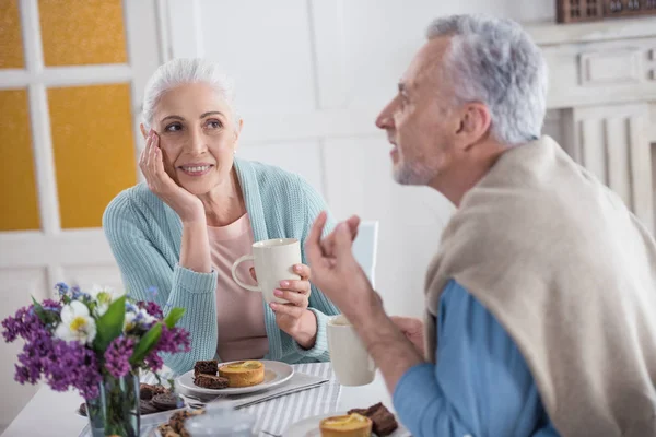 Пожилая пара разговаривает за завтраком — стоковое фото