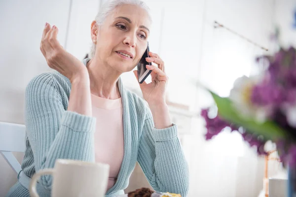 Mujer mayor hablando en el teléfono inteligente en casa - foto de stock