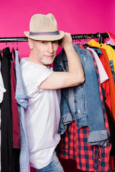 Hombre mayor con ropa diferente en perchas — Stock Photo