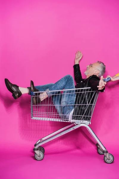 Senior man in shopping trolley — Stock Photo