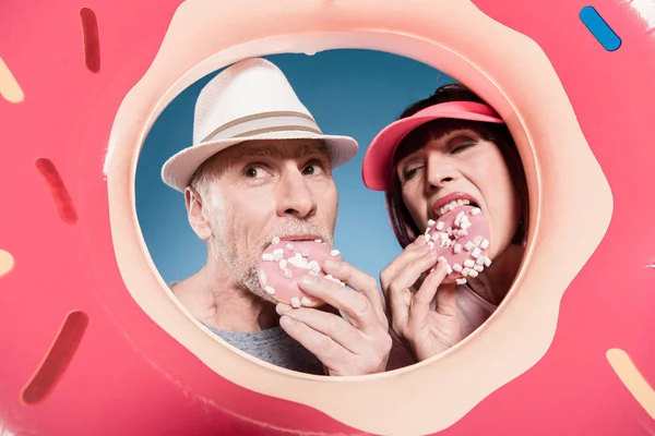 Elderly couple eating sweet doughnuts — Stock Photo