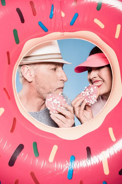 Pareja de ancianos comiendo donas dulces - foto de stock