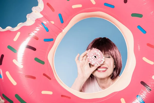 Woman holding doughnut in front of eye — Stock Photo