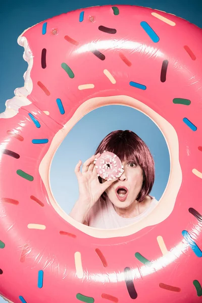 Женщина держит пончик перед глазами — стоковое фото
