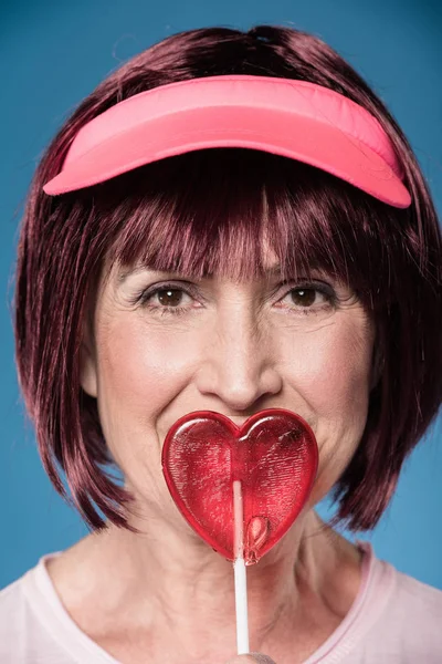 Woman licking lollipop in form of heart — Stock Photo