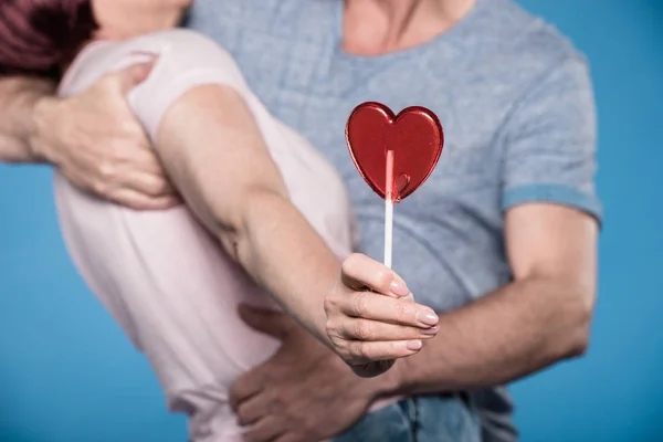 Couple embracing and holding lollipop — Stock Photo