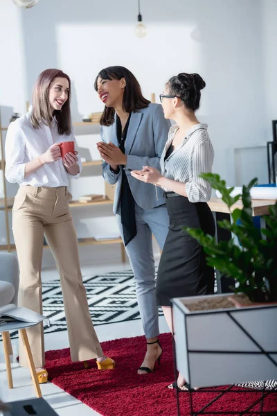 Businesswomen drinking coffee and talking at office — Stock Photo