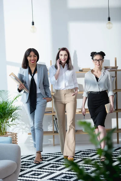 Jóvenes empresarias multiétnicas caminando en la oficina - foto de stock