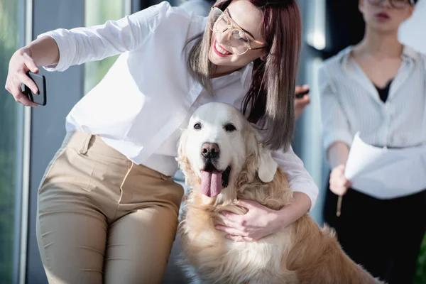 Donna d'affari che prende selfie con cane in ufficio — Foto stock
