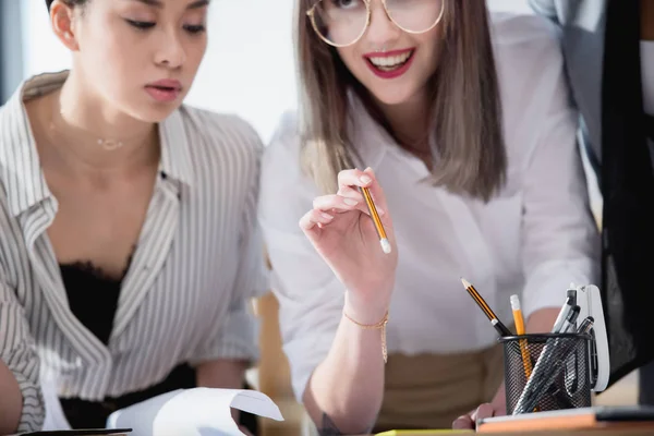 Diseñadores multiétnicos haciendo papeleo en la oficina - foto de stock